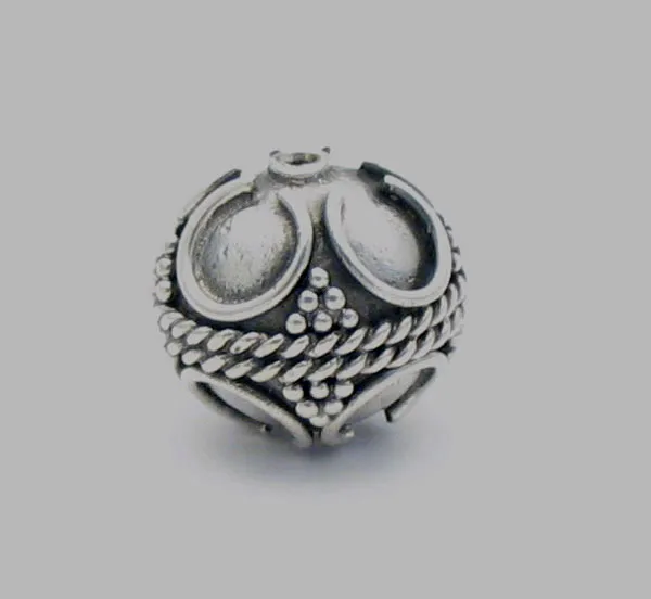 Handcrafted 925 sterling silver spherical bead decorated with traditional Balinese granulation dots, braided rope trim, and horseshoe scrollwork set against an oxidized silver background.