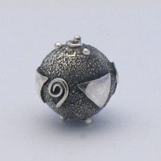 Handcrafted 925 sterling silver spherical bead featuring a stippled oxidized texture, polished spiral motifs, geometric triangle appliqués, and granulated silver accent dots.