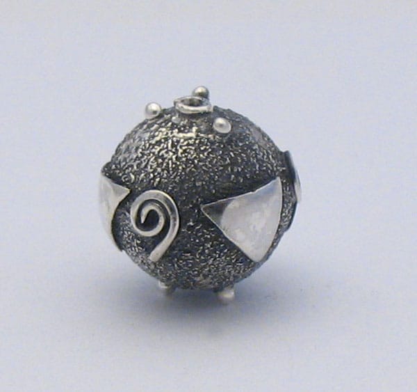 Handcrafted 925 sterling silver spherical bead featuring a stippled oxidized texture, polished spiral motifs, geometric triangle appliqués, and granulated silver accent dots.