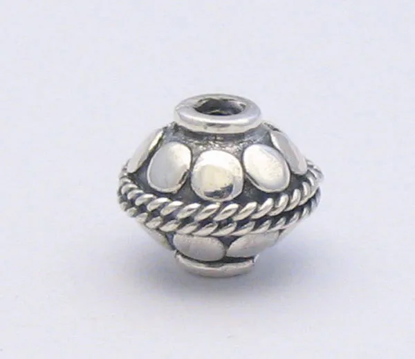 Three-quarter view of a hand-forged 925 sterling silver Balinese rondelle bead featuring a central twisted rope band and raised silver dot details.