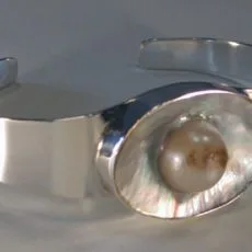 Front perspective view of a sleek 925 sterling silver cuff bracelet featuring a polished wide band and a central oval mother of pearl setting inlaid with a natural cream freshwater pearl.