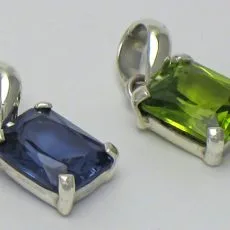 Front view of handcrafted 925 sterling silver solitaire pendants featuring emerald-cut faceted gemstones in four-prong settings with smooth polished bails, shown in vibrant blue gemstone and green peridot options.