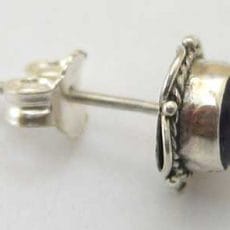 Side perspective view of a handcrafted 925 sterling silver stud earring featuring a smooth dark purple amethyst cabochon in a bezel setting with twisted rope wire trim and a friction post back.