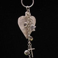 Handcrafted 925 sterling silver openwork heart pendant with carved Balinese scrollwork border and micro-pave set peridot green and clear gemstone butterfly accent.