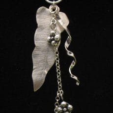 Handcrafted 925 sterling silver pendant featuring a brushed leaf motif, twisted silver ribbon, granulated flower accents, and a dangling cross charm.