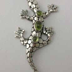 Artisan-crafted 925 sterling silver gecko pendant set with three oval and round cabochon green peridot gemstones on a granulated silver body.
