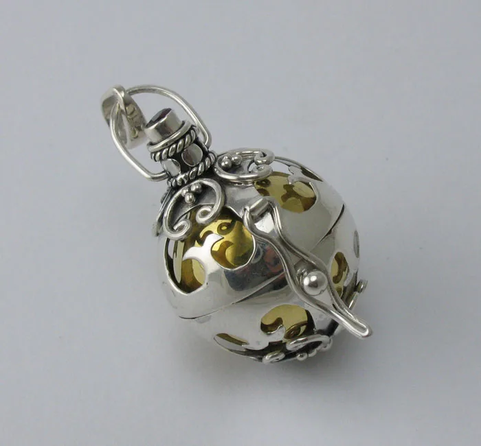 Handcrafted 925 sterling silver spherical harmony ball pendant featuring intricate Balinese scrollwork cutouts, oxidation details, and a polished inner brass chime sphere.