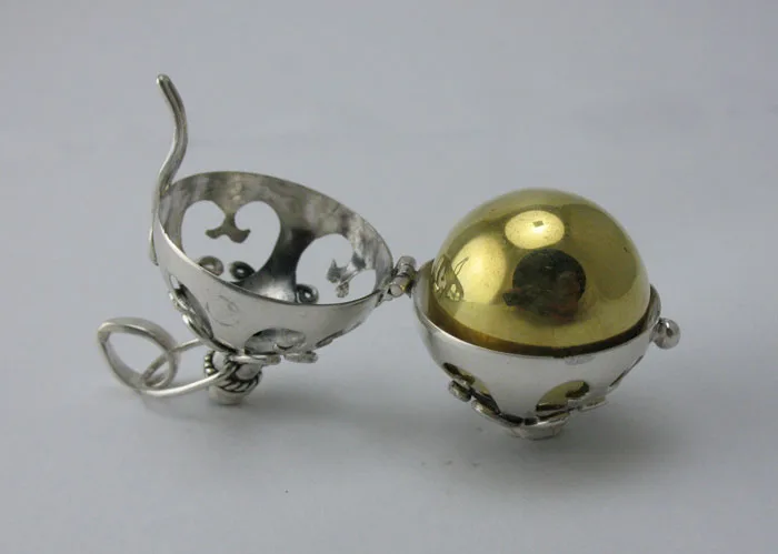 Open hinged view of a Balinese 925 sterling silver locket cage displaying the removable polished brass harmony chime ball inside.