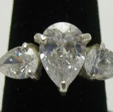 Front macro view of a handcrafted 925 sterling silver trilogy ring featuring a large center pear-cut clear zircon flanked by two smaller pear-shaped gemstones in multi-prong claw settings.