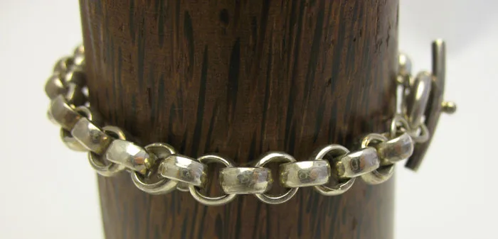 Full length view of the hand-forged 925 sterling silver rollo link chain bracelet draped over a wooden display stand.