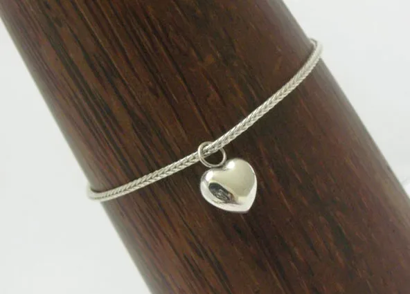 An artisan-crafted 925 sterling silver woven Borobudur chain bracelet displaying a polished puffed heart pendant dangling from a central jump ring.