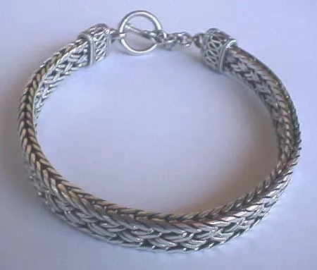 Perspective view of a handcrafted 925 sterling silver wide woven chain bracelet featuring a traditional Balinese Dragonspine weave and a decorative toggle clasp.