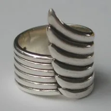 A close-up side view of a sculptural 925 sterling silver ring featuring a layered angel wing design with smooth, polished bands, captured in an artisan-crafted style against a neutral background.