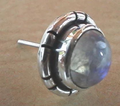 Close-up side profile of a single Balinese-style 925 sterling silver stud earring showcasing a raised round moonstone cabochon within a hand-forged notched silver bezel setting.