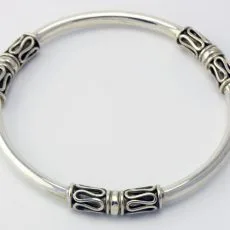 Artisan-crafted 925 sterling silver rigid bangle bracelet featuring three evenly spaced decorative stations adorned with traditional Balinese oxidized scrollwork waves, shown from a direct top-down perspective against a plain white background.