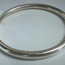 Artisan-crafted 925 sterling silver rigid bangle bracelet featuring a completely smooth tubular band with a brilliant high-polish surface finish, displayed at a three-quarter angle against a neutral background.
