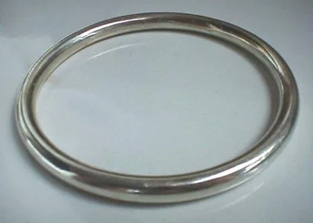 Artisan-crafted 925 sterling silver rigid bangle bracelet featuring a completely smooth tubular band with a brilliant high-polish surface finish, displayed at a three-quarter angle against a neutral background.
