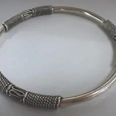 Hand-forged 925 sterling silver bangle bracelet featuring three distinct artisan-crafted stations with detailed rope textures and oxidized Balinese geometric wirework accents on a polished silver band
