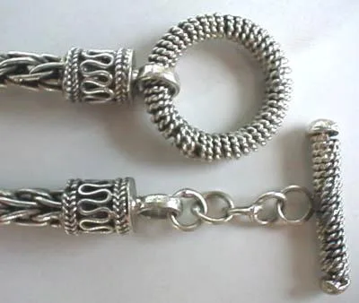 Close-up of an intricate Balinese-style 925 sterling silver toggle clasp and scrollwork end caps on a woven chain.