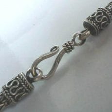 Detailed macro view of an artisan 925 sterling silver S-hook clasp on a woven chain necklace, featuring ornate end caps decorated with S-scroll filigree and twisted rope borders.