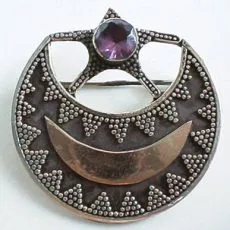 Front view of a handcrafted 925 sterling silver circular brooch pin featuring a central star set with a faceted purple amethyst, a smooth warm-toned crescent moon inlay, and intricate Balinese triangular granulation on an oxidized background.