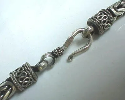 Close-up of a hand-forged S-hook clasp and detailed filigree end caps on a 925 sterling silver necklace.