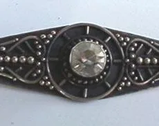 Front view of a handcrafted 925 sterling silver elongated bar brooch featuring a central round clear quartz gemstone set in a sunburst wheel motif, framed by intricate Balinese wirework, granulation dots, and deep antiqued oxidation.