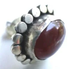 Close-up side view of a handcrafted 925 sterling silver stud earring featuring an oval carnelian cabochon set in a bezel surrounded by granulated silver beads.