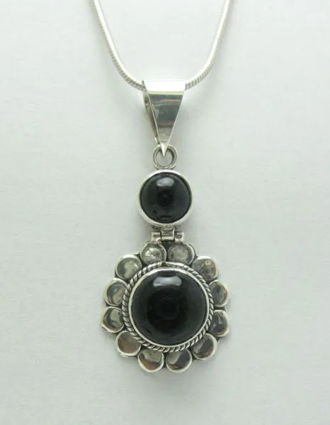 Front-facing studio photograph of the artisan-crafted sterling silver stacked sunburst pendant holding two polished black onyx stones against a light background.