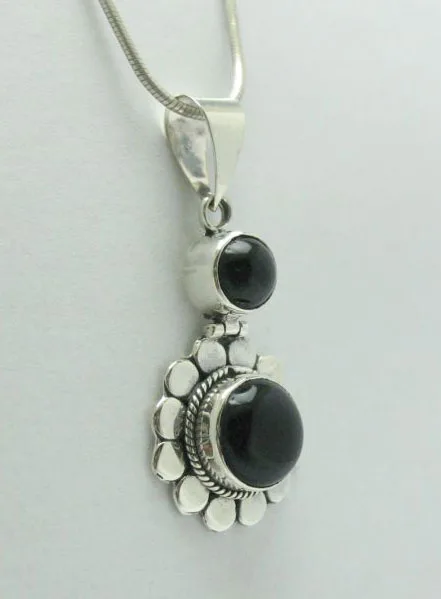 Side view of a hand-forged 925 sterling silver stacked pendant showcasing two deep black onyx cabochons within ornate Balinese beadwork borders.