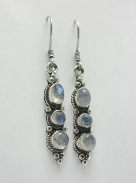 Close-up studio view of triple moonstone drop earrings showcasing iridescent blue flash in the stones and traditional Balinese-style silver work on a white background.