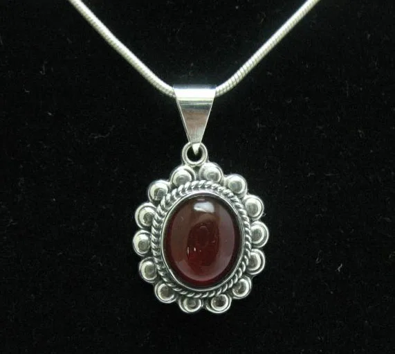 Front-facing studio shot of a hand-forged sterling silver sunburst pendant featuring an oval carnelian stone with detailed silver beadwork.
