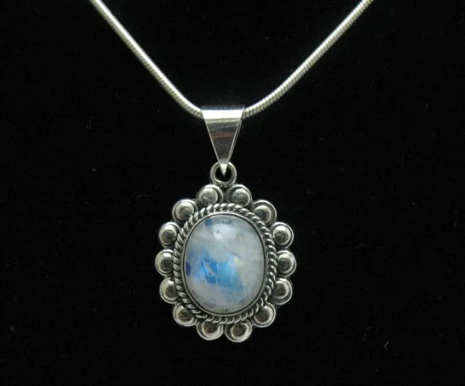 Front-facing studio shot of a hand-forged sterling silver sunburst pendant featuring an oval carnelian stone with detailed silver beadwork.