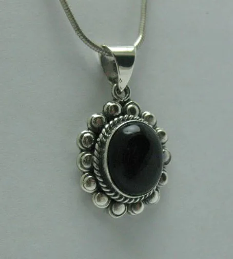 Angled profile shot of a polished 925 sterling silver pendant set with a glossy oval black onyx cabochon against a neutral background.