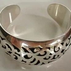 A wide 925 sterling silver openwork cuff bracelet featuring an intricate, oxidized Batik cutout pattern with a highly polished finish.