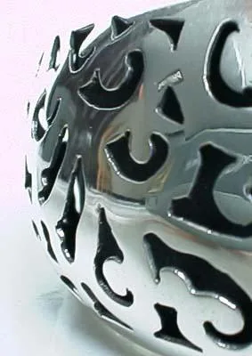 A close-up shot highlighting the detailed openwork, deep oxidized accents, and polished smooth edges of a hand-forged sterling silver cuff bracelet.