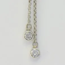 Close-up view of clear round-cut gemstones in 925 sterling silver bezel settings attached to delicate drop chains.